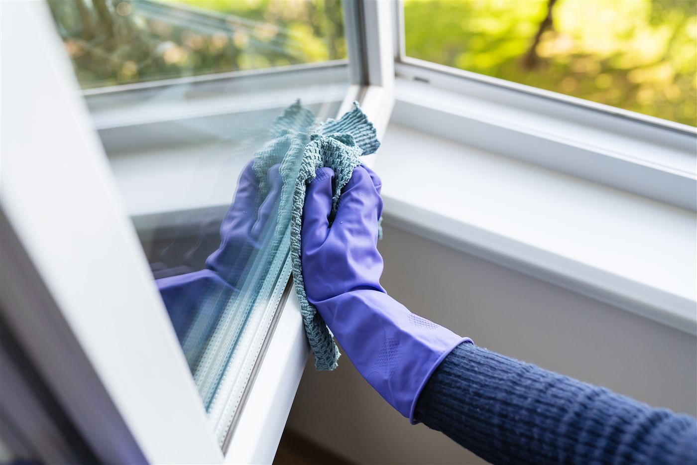 Gloved hands cleaning a window pane until it sparkles, ready for viewings in Airdrie